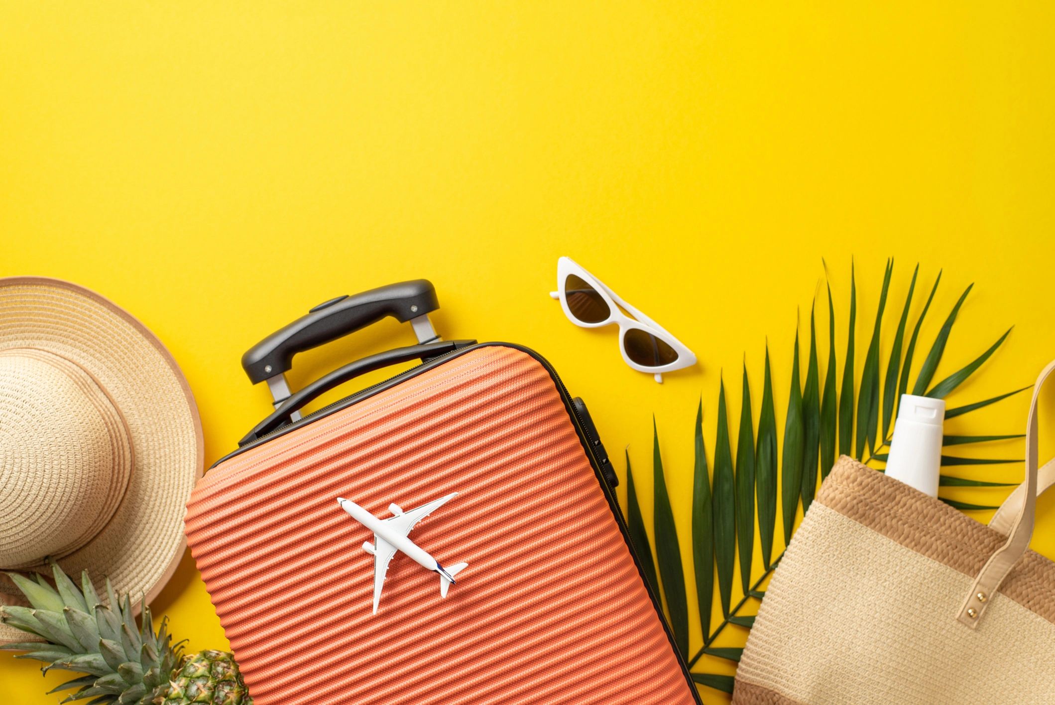 Orange suitcase with travel accessories arranged in a flat lay